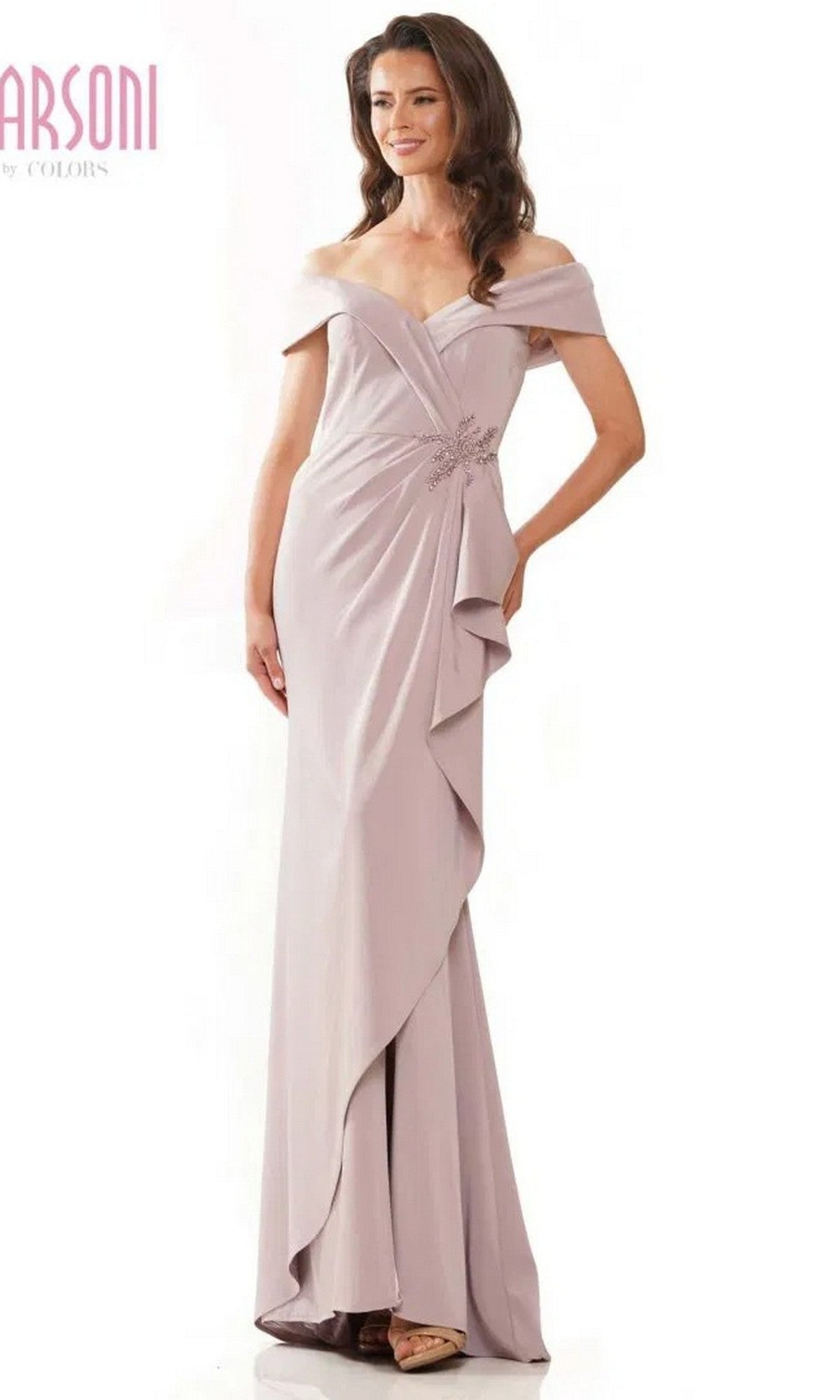A woman wears the Marsoni MV1180 long formal dress in dusty rose, an off-the-shoulder gown with a floor-length draped asymmetrical skirt and a beaded waistline adorned with floral embellishments.